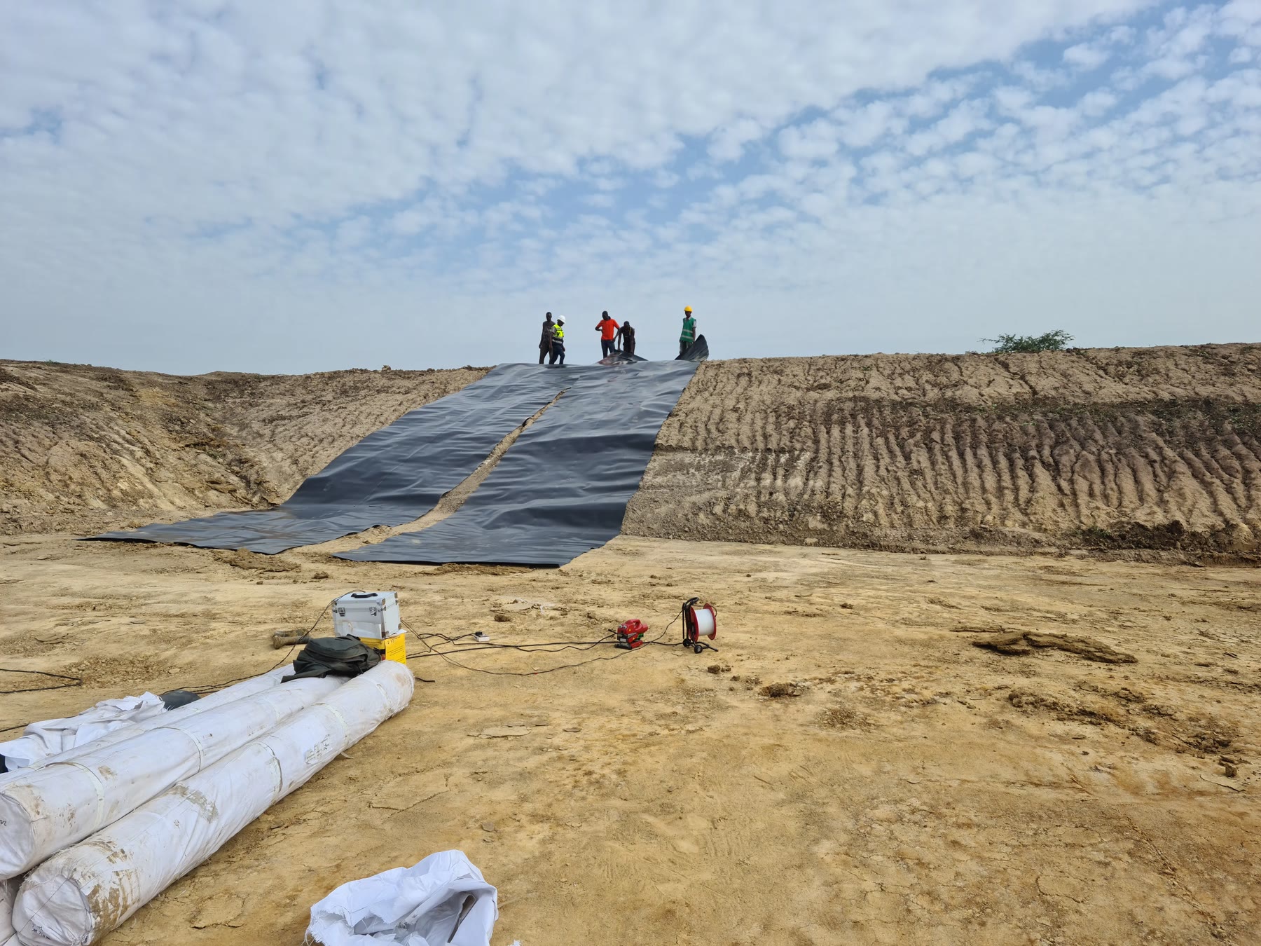 Team installing a geomembrane liner in an excavated farm reservoir